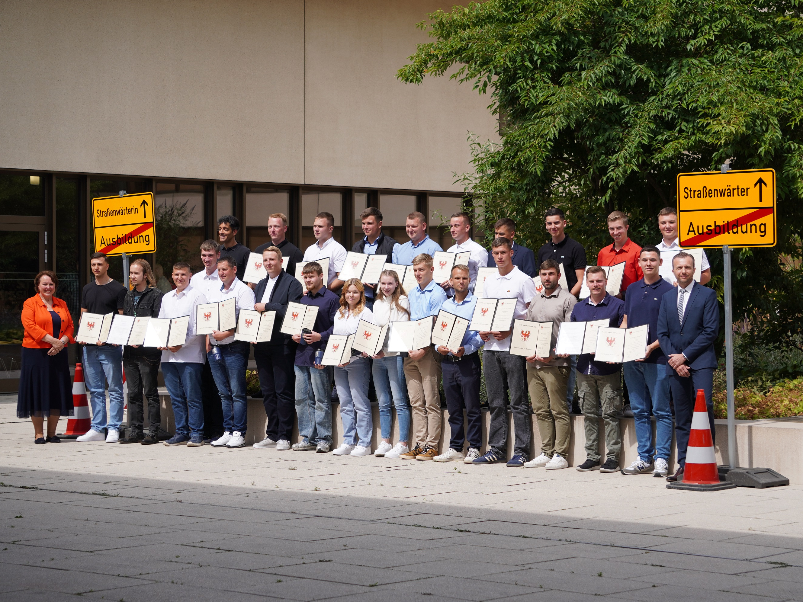 Feierliche Freisprechung 2025 Gruppenfoto mit freigesprochenen Straßenwärterinnen und Straßenwärtern vorne links Staatssekreärin Dr. Ina Bartmann und vorne rechts Mike Koehler Vorsitzender des Vorstrands beim Landesbetrieb Straßenwesen